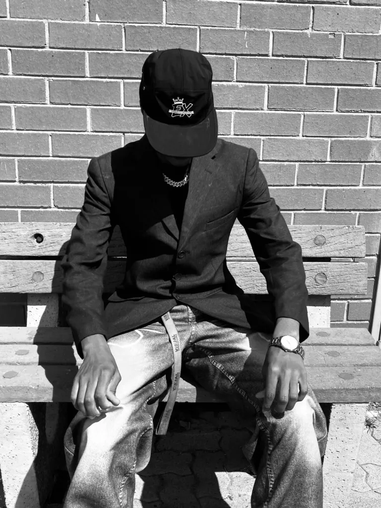 Black-and-white lifestyle photograph of an Exclusive Apparel cap styled with a blazer
