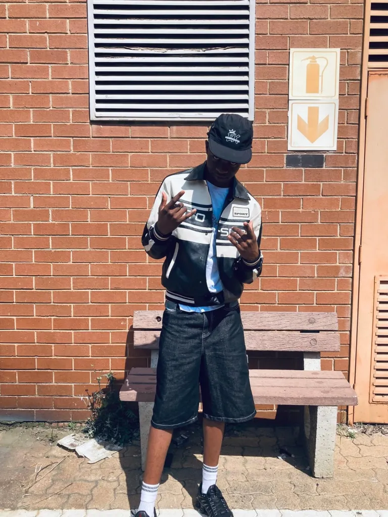 Black Exclusive Apparel cap styled with a two-tone jacket and denim shorts